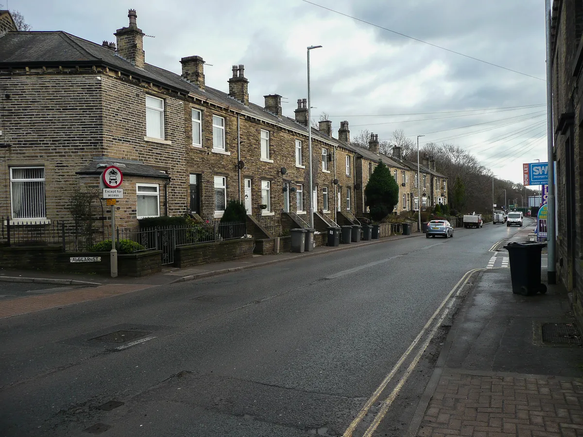 A row of stone terraced houses with tall chimneys along Wakefield Road, Brighouse